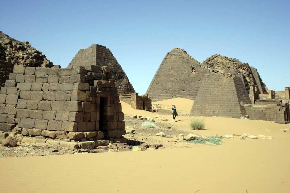 A visitor walks past pyramids in the cemetary of Meroe north of Khartoum, Sudan [EBRAHIM HAMID/AFP via Getty Images]